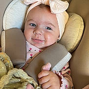 Lùna participe au concours pour gagner de l'argent avec cette photo : baby, infant, car_seat, headband, bow, pink, blanket, toy, braided_toy, clothing, straps, face, hand, smiling, child, seat, safety, closeup, indoor, warning_label