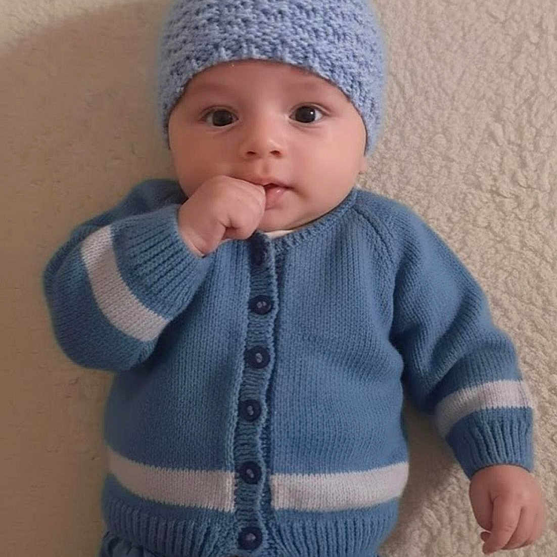 Loay a rejoint le concours — aidez-le/la à gagner de superbes lots ! baby, blue_hat, buttoned_sweater, casual, child, cozy_clothing, curious_eyes, cute, denim_pants, face, hand, indoor, infant, knitwear, lying_down, portrait, soft_texture, sweater, thumb_in_mouth, young_child