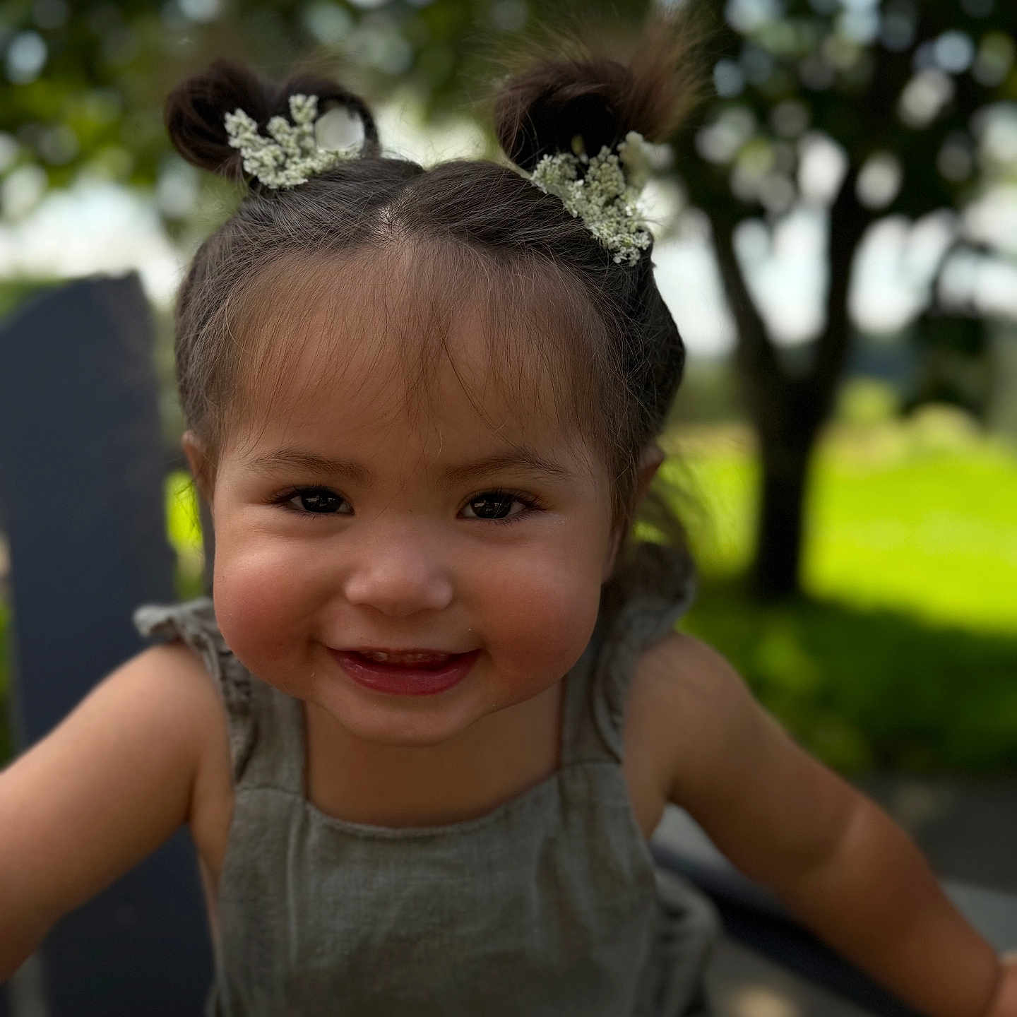 Valeria joined the competition — help win amazing prizes! baby, casual_clothing, child, cute, daylight, face, flowers, greenery, hair_buns, happy, nature, outdoor, person, portrait, sitting, skin, smiling, sunlight, toddler, young_child