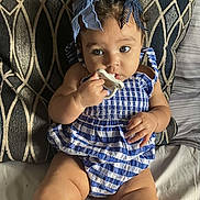 Jahnova is registered to the contest to win money with this photo: baby, child, pacifier, blue_bow, curly_hair, striped_outfit, pillow, patterned_background, sitting, indoors, cute, chubby, infant, hand, face, eyes, legs, skin, comfort, portrait