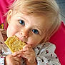 toddler, child, blue_eyes, cracker, snack, hand, face, blond_hair, floral_clothing, pink_background, cute, portrait, indoor, person, baby, eating, closeup, expression, small_hands, cozy