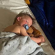 Jayden is registered to the contest to win money with this photo: arm, bed, blanket, child, comfort, cozy, face, hair, indoors, nap, pacifier, pillow, quiet, rest, skin, sleeping, soft, teddy_bear, toddler, toy