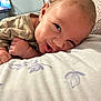 Zayden is registered to the contest to win money with this photo: baby, infant, smiling, face, closeup, pillow, pattern, striped_clothing, hand, skin, indoor, bedroom, person, young_child, curious, lying_down, cute, head, expression, soft_light