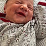 baby, newborn, smile, sleeping, onesie, dog_pattern, clothing, infant, cute, happy, face, portrait, child, sleep, bed, blanket, fabric, closeup, person, indoors