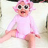 baby, child, pink, sunglasses, hat, striped_clothing, smiling, happy, sitting, couch, indoor, cute, face, headwear, fashion, infant, playful, person, accessory, portrait