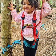 Syrine a rejoint le concours — aidez-le/la à gagner de superbes lots ! child, girl, forest, rope_net, harness, safety_gear, pink_jacket, curly_hair, smiling, outdoor, trees, adventure_park, footwear, pink_bows, playground, nature, young_child, happy, rope, balance