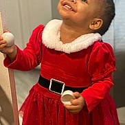 Liamani joined the competition — help win amazing prizes! toddler, child, smiling, red_dress, holiday_outfit, indoor, holding_object, door_frame, happy, person, young_child, festive_clothing, cute, portrait, celebration, girl, bright_colors, face, looking_up, candid