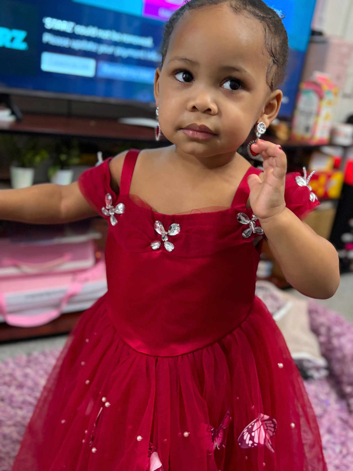Liamani joined the competition — help win amazing prizes! child, toddler, dress, red_dress, butterfly, earrings, indoor, living_room, television, person, cute, jewelry, decorative, furniture, carpet, expression, young_child, home, portrait, fashion