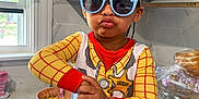Liamani joined the competition — help win amazing prizes! toddler, child, sunglasses, costume, sheriff_badge, kitchen, countertop, snacks, chips_ahoy, bowl, food, hand, window, cabinet, person, playful, pose, blue_pants, red_cuffs, indoors