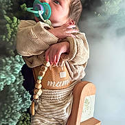 Mathis a rejoint le concours — aidez-le/la à gagner de superbes lots ! baby, pacifier, clothing, wooden_toy, number_one, beads, face, hand, infant, portrait, cute, child, indoor, soft_lighting, texture, natural_background, person, expression, young, holding