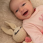 Mia participe au concours pour gagner de l'argent avec cette photo : baby, smiling, infant, knitted_toy, bunny, soft_texture, blanket, pink_clothing, cute, happy, lying_down, cozy, child, toddler, plush_toy, face, closeup, indoor, portrait, snuggling