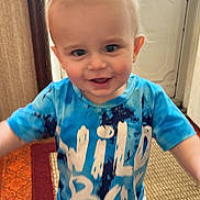 Waylon is registered to the contest to win money with this photo: toddler, child, indoor, standing, blue_shirt, tie_dye, happy, curious, hair, carpet, door, motion_blur, face, person, clothing, young_child, home, smile, barefoot, floor