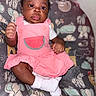 baby, infant, pink_dress, watermelon_patch, cushion, animal_print, elephant, sloth, zebra, whale, cloud, smiling_face, white_socks, dark_skin, curly_hair, indoor, portrait, child, cute, seated