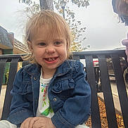 Zoey joined the competition — help win amazing prizes! toddler, child, smiling, denim_jacket, bench, outdoor, tree, sidewalk, building, vehicle, adult, person, casual_clothing, daytime, happy, portrait, urban, fall, parked_car, overcast_sky