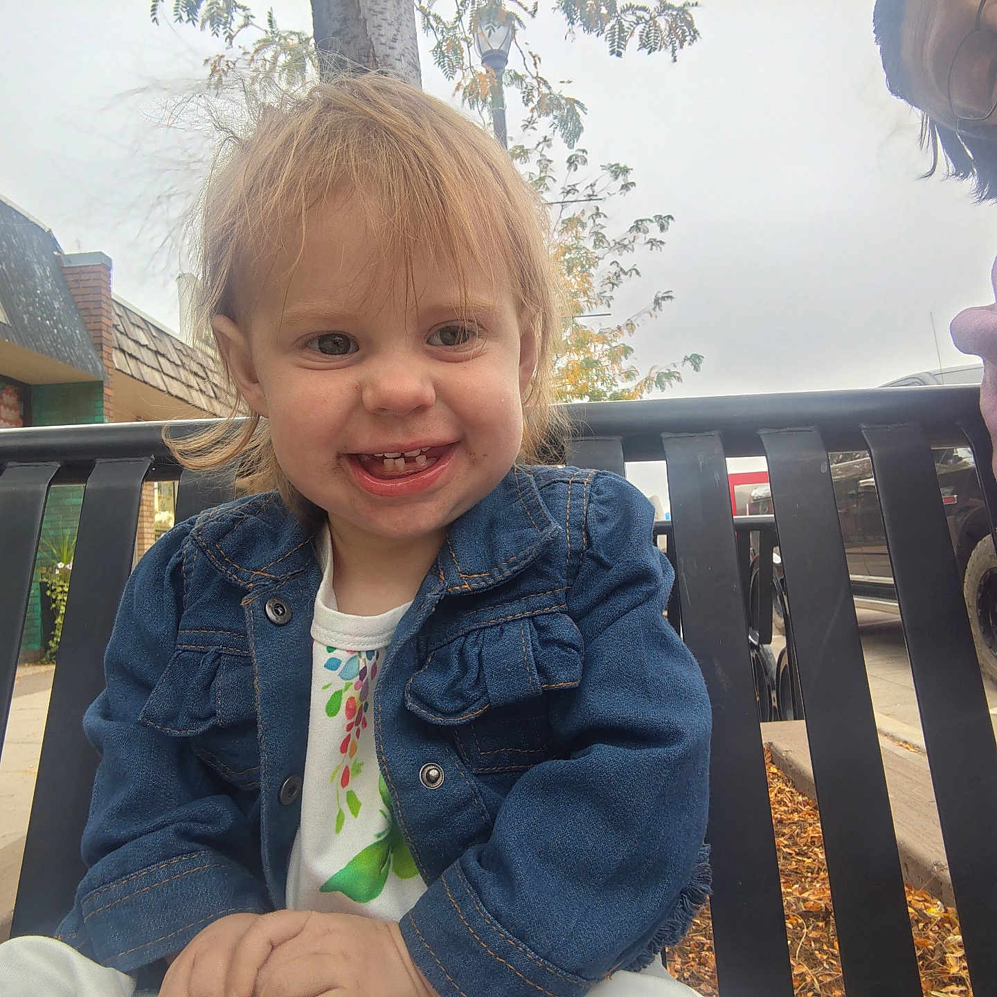 Zoey joined the competition — help win amazing prizes! adult, bench, building, casual_clothing, child, daytime, denim_jacket, fall, happy, outdoor, overcast_sky, parked_car, person, portrait, sidewalk, smiling, toddler, tree, urban, vehicle