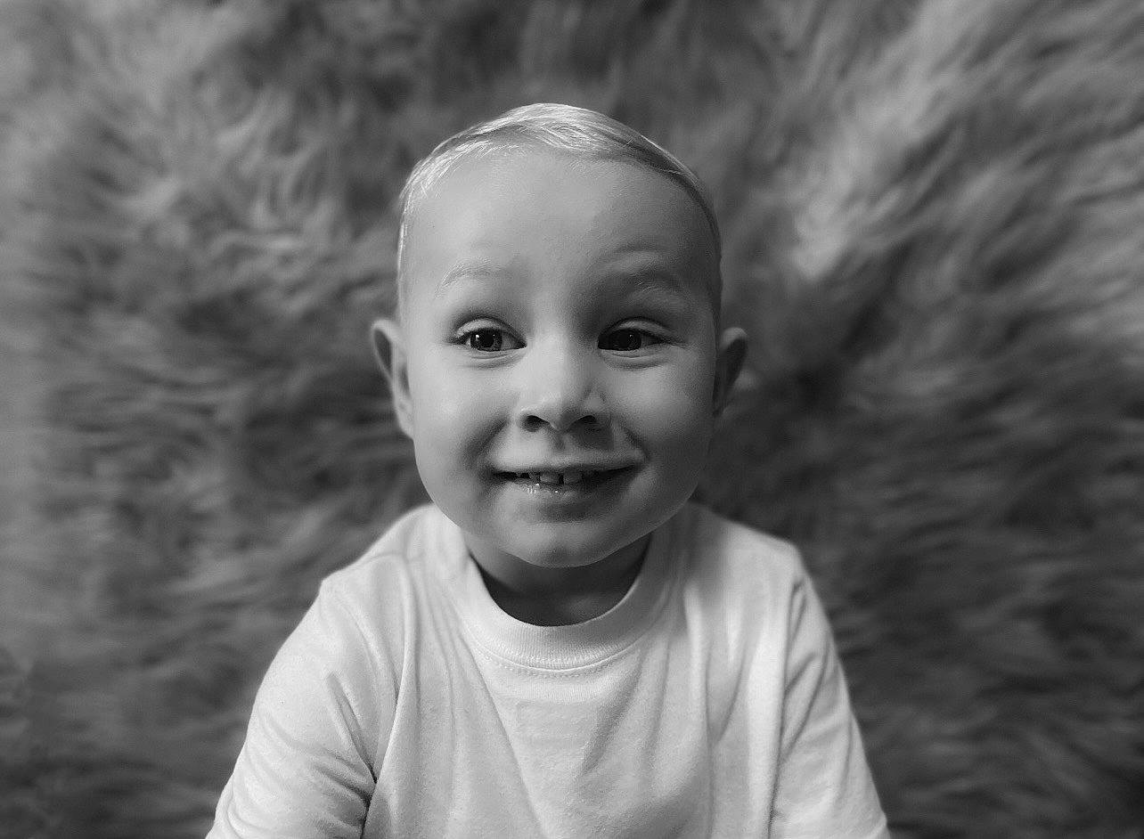 Jaxtyn is registered to the contest to win money with this photo: black_and_white, child, eye, eyebrow, face, flash_photography, grass, happy, iris, joy, monochrome, monochrome_photography, nose, people_in_nature, person, plant, smile, standing, style, t_shirt
