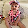 Aitana is registered to the contest to win money with this photo: toddler, child, baby, pink_clothing, cap, sitting, couch, white_leather, indoor, cute, smile, face, person, toy, relaxed, legs, hands, headwear, casual, cozy