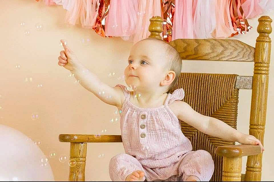 Wren is registered to the contest to win money with this photo: baby, baby_toddler_clothing, chair, cheek, child, event, eye, fashion_accessory, fun, happy, headpiece, lighting_accessory, magenta, party_supply, peach, person, pink, room, sitting, toddler