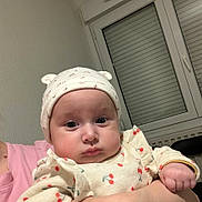 Salima participe au concours pour gagner de l'argent avec cette photo : baby, child, hat, clothing, person, face, expression, indoor, window, curious, cute, holding, pink_shirt, cherry_pattern, hand, headwear, infant, portrait, serious, skin