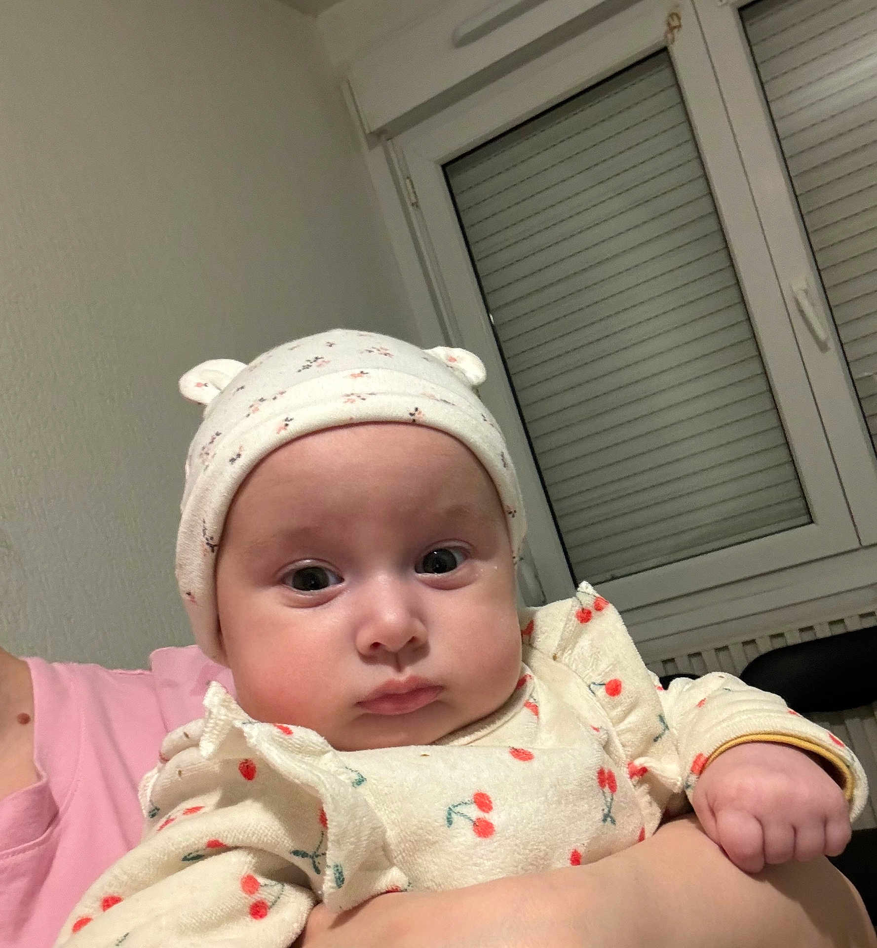 Salima participe au concours pour gagner de l'argent avec cette photo : baby, child, hat, clothing, person, face, expression, indoor, window, curious, cute, holding, pink_shirt, cherry_pattern, hand, headwear, infant, portrait, serious, skin