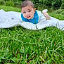 baby, blanket, blue_bib, child, clothing, cute, daylight, face, grass, greenery, happy, head, infant, lying_down, nature, outdoor, pond, portrait, smiling, trees