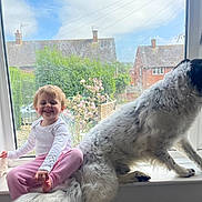 Arlia joined the competition — help win amazing prizes! toddler, child, dog, windowsill, window, smiling, pink_pants, white_shirt, pet, house, garden, flower, daylight, indoor, furry, happy, playing, domestic_animal, window_view, casual_clothing