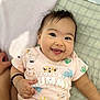 adorable, animal_print, baby, child, cute, expression, face, hand, happy, indoors, infant, lying_down, pastel_colors, playful, portrait, shirt, smiling, soft_surface, text_on_clothing, toddler