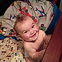 baby, child, smiling, crib, blanket, bedding, mohawk, nursery, wooden_rail, indoor, happy, cute, infant, person, playful, cartoon, colorful, fabric, bedroom, toddler