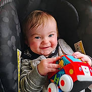 Jaxon joined the competition — help win amazing prizes! baby, blue, car_seat, child, clothing, cute, face, hands, happy, indoor, infant, person, playful, portrait, red, seat_belt, smiling, striped_shirt, toy, white