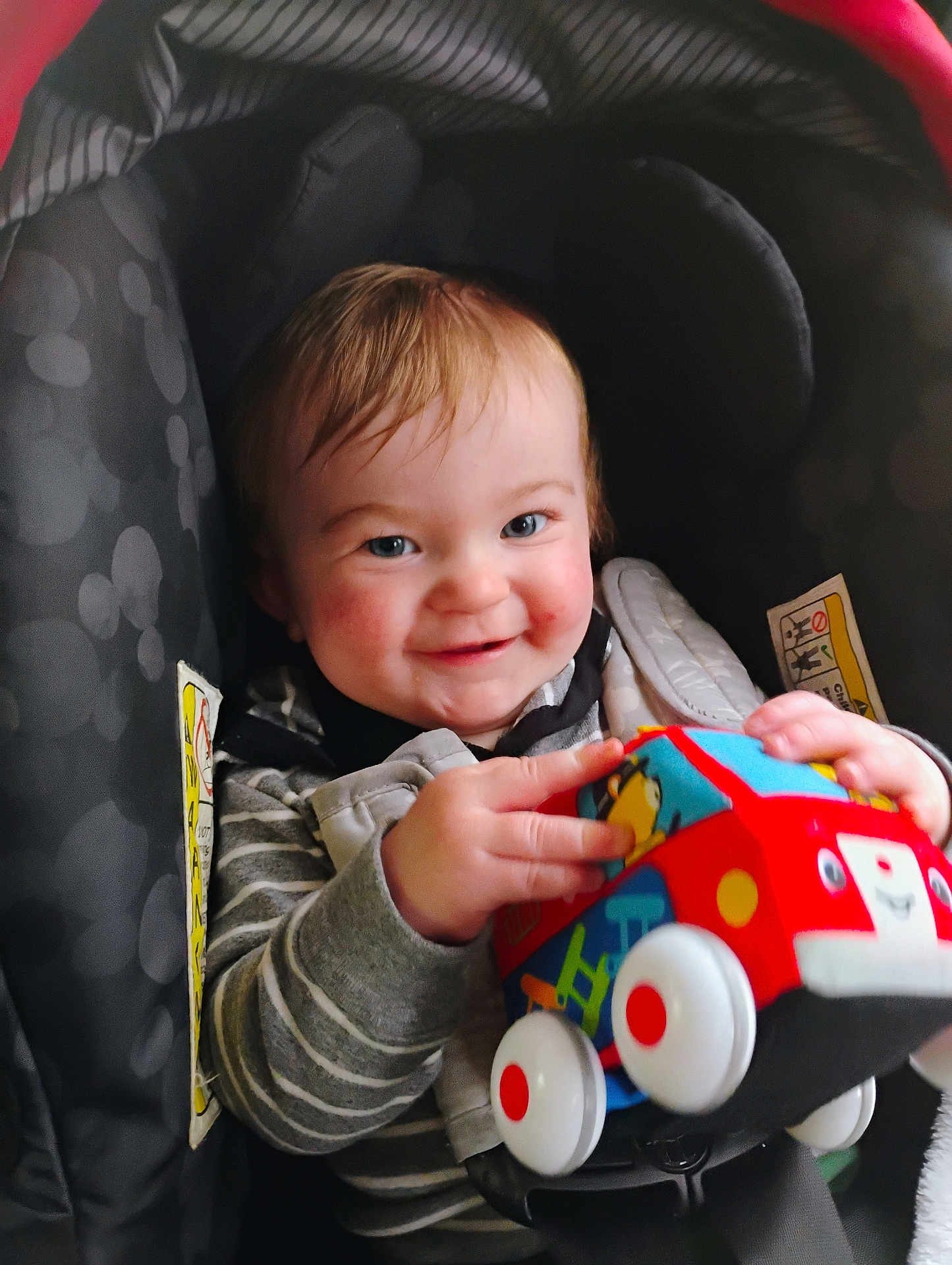 Jaxon joined the competition — help win amazing prizes! baby, blue, car_seat, child, clothing, cute, face, hands, happy, indoor, infant, person, playful, portrait, red, seat_belt, smiling, striped_shirt, toy, white