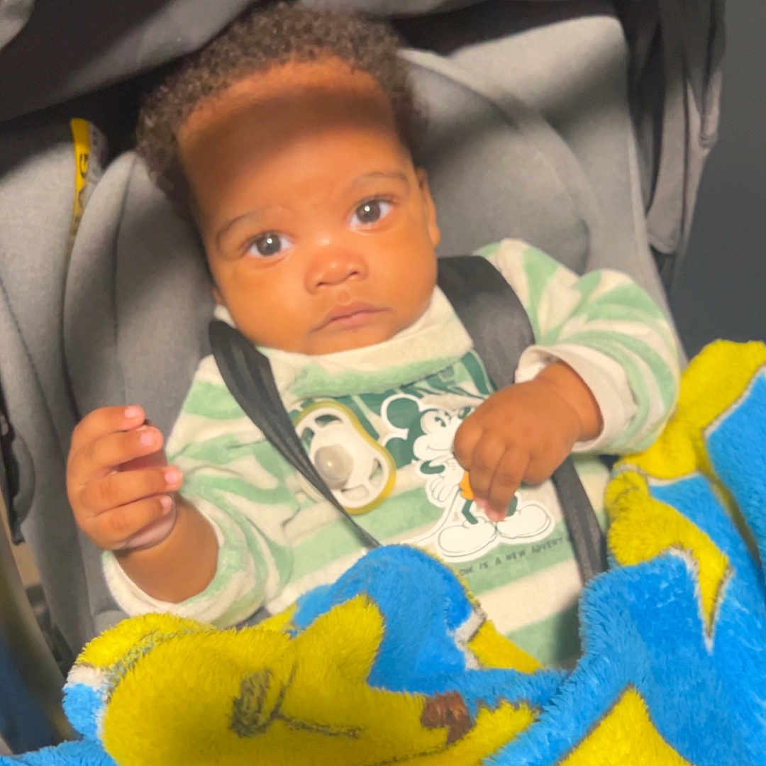 Dayane participe au concours pour gagner de l'argent avec cette photo : baby, blanket, cartoon, child, clothing, comfort, cozy, curly_hair, cute, indoor, infant, looking, mickey_mouse, pacifier, portrait, seated, soft_toy_pattern, striped_clothing, stroller, young_child