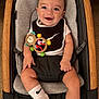 baby, baby_seat, black_and_white_clothing, carpet, child, comfortable, cute, happy, indoors, infant, monkey_toy, nike, playful, portrait, seated, smiling, socks, toy, wooden_frame, young_child