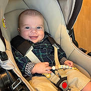 ézio a rejoint le concours — aidez-le/la à gagner de superbes lots ! baby, smiling, stroller, plaid_shirt, beige, toy, indoor, child, happy, clothing, seatbelt, foot, hand, fabric, person, infant, cute, comfort, young, face