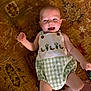 Jon Lewis is registered to the contest to win money with this photo: baby, infant, smiling, lying_down, child, cute, green_checkered, outfit, patterned_rug, floor, hand, foot, playful, happy, indoors, person, young_child, skin, head, expression