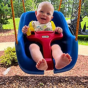 Jon Lewis joined the competition — help win amazing prizes! baby, child, swing, outdoor, playground, grass, trees, sunny, smiling, happy, blue_swing, red_safety_bar, yellow_straps, feet, rocks, golf_cart, greenery, daylight, person