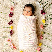 Cianna is registered to the contest to win money with this photo: newborn, baby, wrapped, blanket, crochet, flowers, circle, soft, rug, pastel, pink, yellow, purple, white, green, peaceful, portrait, infant, cute, lying_down