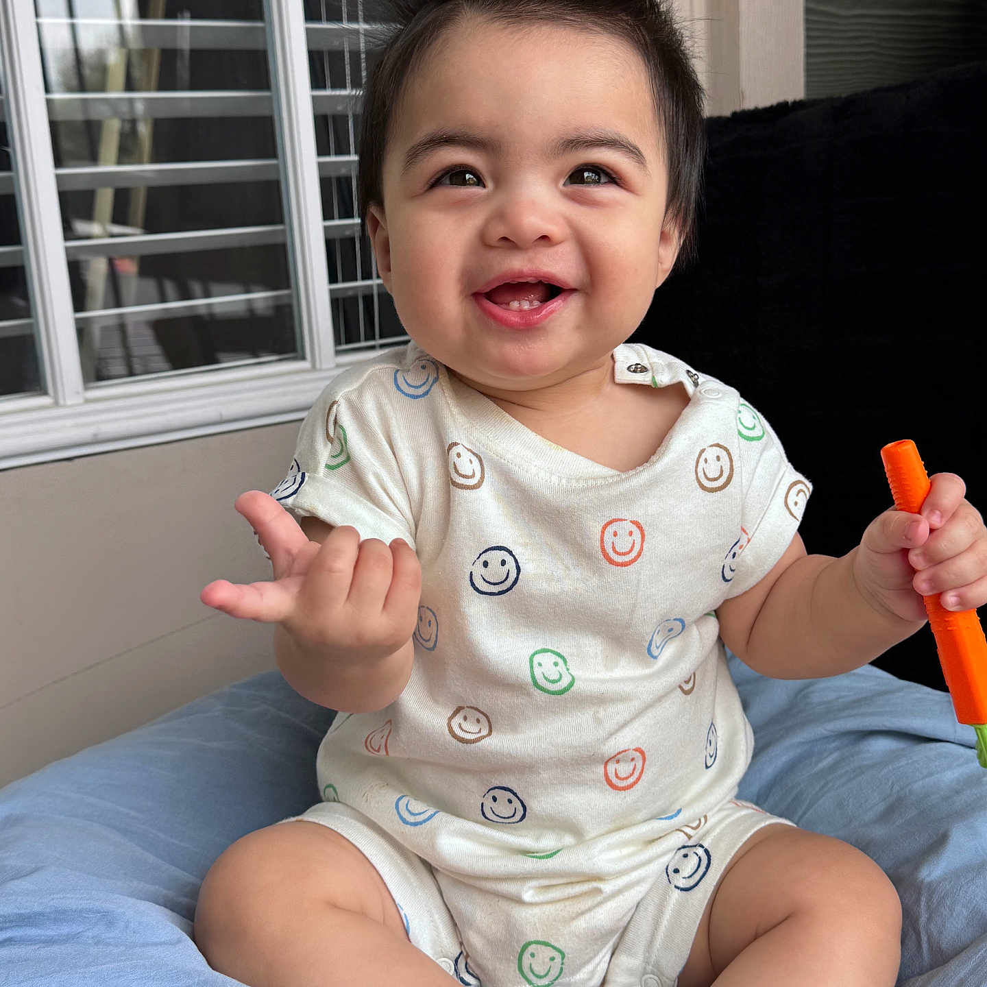 Maximiliano joined the competition — help win amazing prizes! baby, background, child, clothing, cushion, cute, expression, face, hair, hand_gesture, happy, indoor, infant, onesie, person, sitting, skin, smiling, toy, window