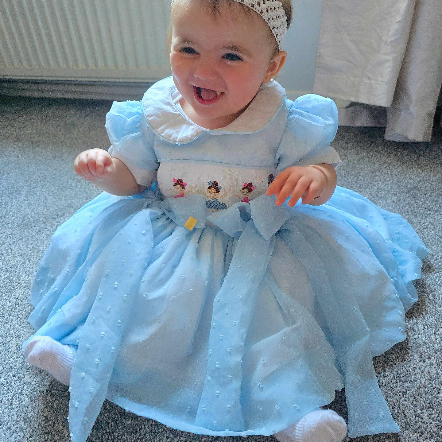 Milanna-Skye joined the competition — help win amazing prizes! baby, blue_dress, carpet, child, clothing, curtain, cute, flower, happy, headband, indoor, infant, person, portrait, radiator, sitting, smiling, toddler, white_socks, young_child