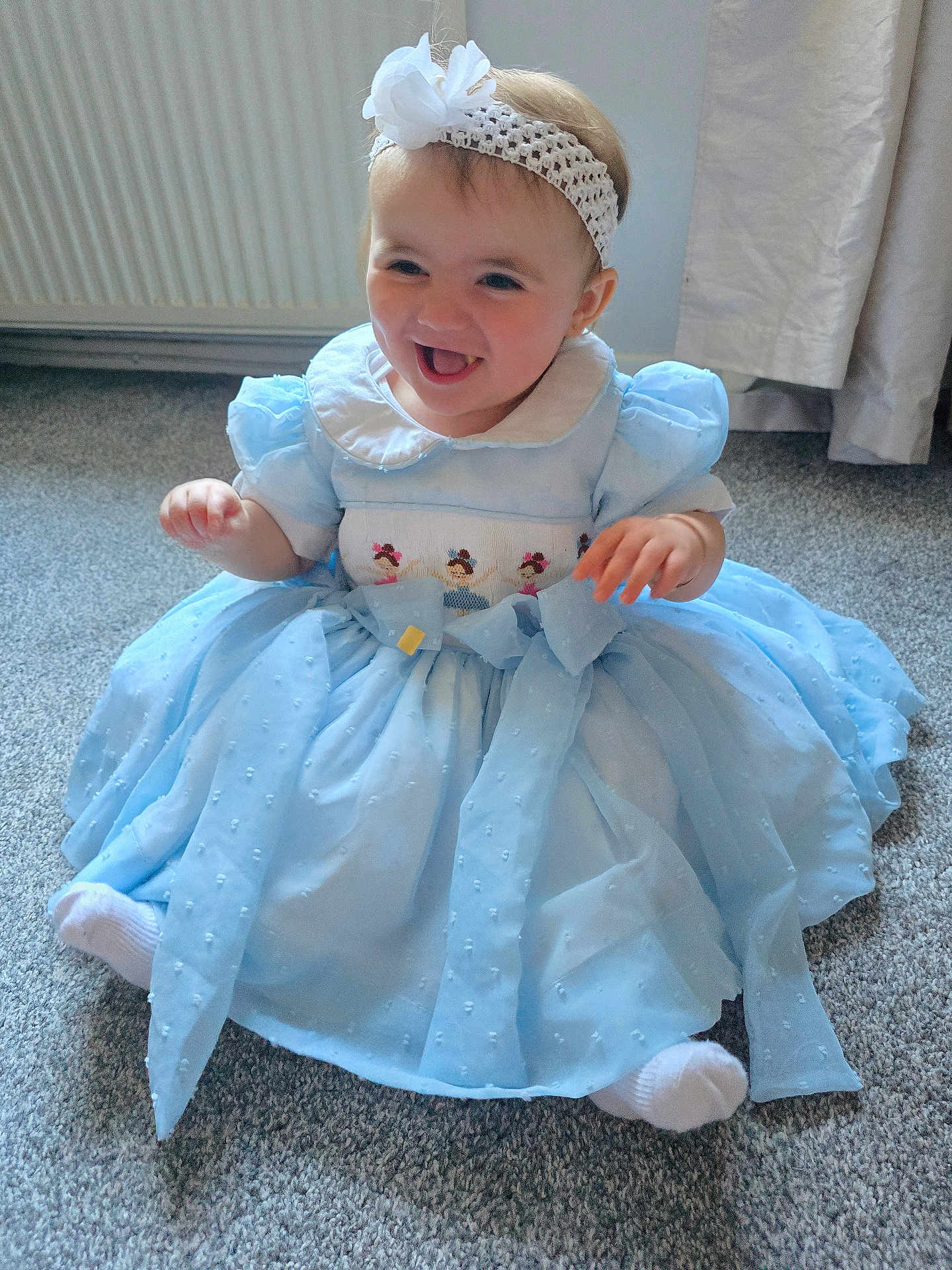 Milanna-Skye joined the competition — help win amazing prizes! baby, blue_dress, carpet, child, clothing, curtain, cute, flower, happy, headband, indoor, infant, person, portrait, radiator, sitting, smiling, toddler, white_socks, young_child
