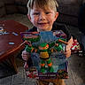 Grayson joined the competition — help win amazing prizes! child, boy, toy, teenage_mutant_ninja_turtles, smile, living_room, couch, carpet, table, puzzle_pieces, barefoot, happy, packaging, plastic_toy, brown_pants, black_shirt, indoor, furniture, home, person