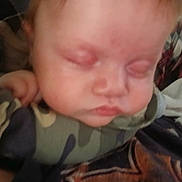 Dollyne is registered to the contest to win money with this photo: baby, sleeping, face, child, infant, camouflage_clothing, hand, bottle, resting, close_up, soft_light, peaceful, portrait, indoor, person, young_child, cuddly, blurred, skin, head