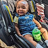 baby, car_seat, denim_overall, smiling, child, sippy_cup, toy, pink, yellow_shirt, curly_hair, indoor, seatbelt, car_interior, happy, cute, infant, portrait, clothing, hands, feet
