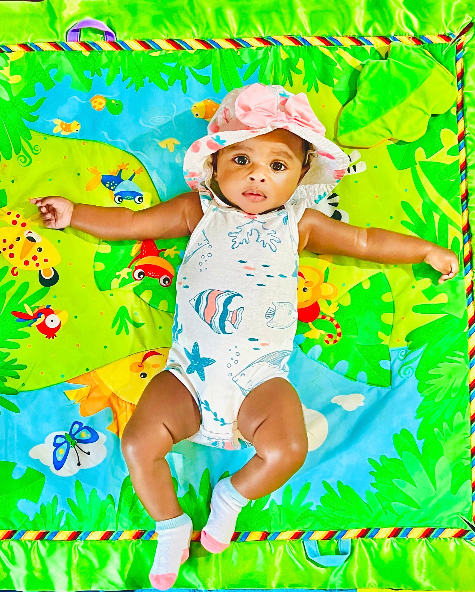 Lisa is registered to the contest to win money with this photo: baby_toddler_clothing, child, electric_blue, foot, fun, graphics, grass, happy, hat, headwear, human_leg, leisure, nature, pattern, people_in_nature, person, play, sandal, sitting, sun_hat