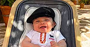 Mylan a rejoint le concours — aidez-le/la à gagner de superbes lots ! baby, child, smiling, stroller, beret, clothing, outdoor, potted_plants, flowers, sign, door, courtyard, sunlight, shadow, happy, person, red_clothing, white_shirt, yellow_belt, spain