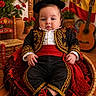 Mylan participe au concours pour gagner de l'argent avec cette photo : baby, child, traditional_clothing, spanish_outfit, hat, red_flowers, guitar, spanish_flag, woven_basket, shawl, decorative_chair, pottery, portrait, indoor, colorful, cultural, smiling, cute, happy, festive