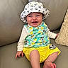 Mylan participe au concours pour gagner de l'argent avec cette photo : baby, child, smiling, hat, mickey_mouse, clothing, yellow_shorts, sitting, couch, leather, happy, infant, face, cute, portrait, indoor, person, apparel, foot, hand