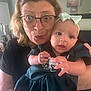 Layla Rose is registered to the contest to win money with this photo: baby, child, woman, elderly, glasses, headband, dress, indoor, living_room, ceiling_fan, portrait, holding, curious, expression, person, clothing, face, hand, home, family