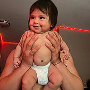 Genesis Andrea Muñoz joined the competition — help win amazing prizes! baby, diaper, smile, hands, adult, indoor, ceiling_light, red_led_light, person, skin, child, cute, happy, infant, plump, holding, human, room, expression, portrait