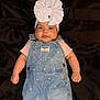Genesis Andrea Muñoz joined the competition — help win amazing prizes! baby, infant, child, denim_overalls, headband, bow, pink_shirt, cute, smiling, fist, lying_down, black_blanket, clothing, portrait, adorable, face, young_child, fashion, indoor, closeup