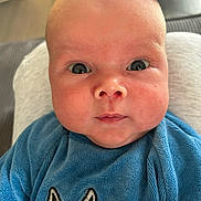 Sohan participe au concours pour gagner de l'argent avec cette photo : baby, close_up, blue_clothing, bunny_design, chubby_cheeks, curious_expression, infant, indoors, person, portrait, soft_texture, wide_eyes, cute, young_child, head, face, sitting, looking_at_camera, skin, newborn